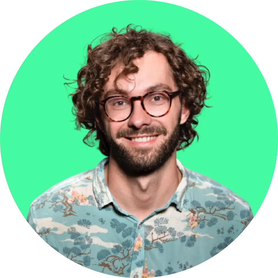 Louis Graham, the founder of the company. Light brown hair, beard, glasses and lovely smile wearing blueish t-shirt with pattern of trees on it.